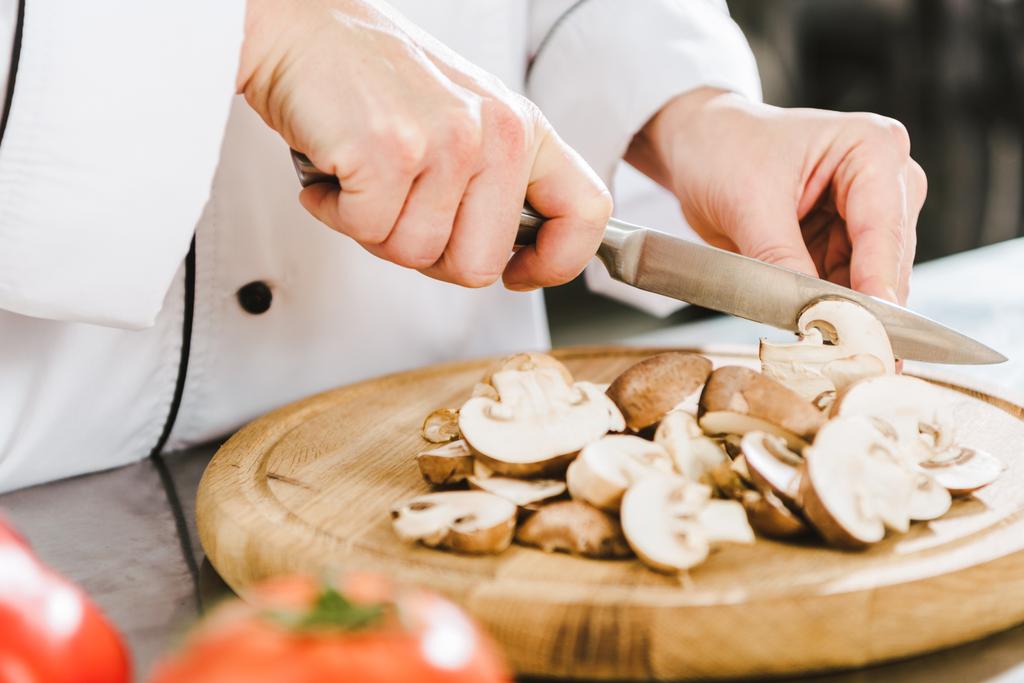 частковий вид на жіночого шеф-кухаря, який ріже гриби на кухні ресторану
 - Фото, зображення