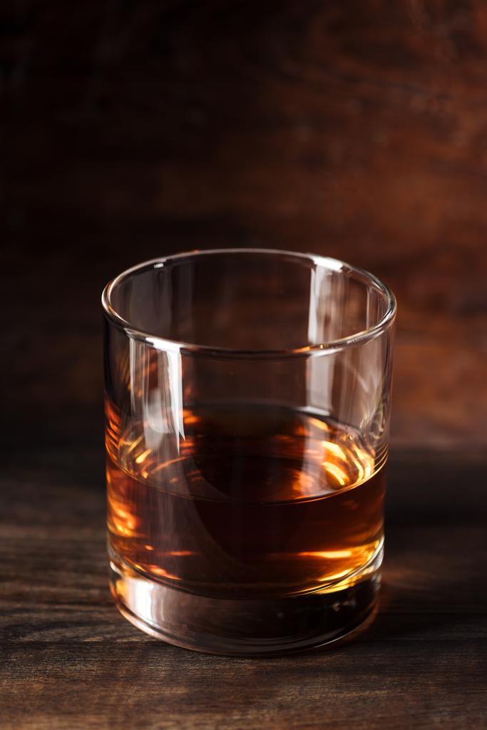 Nahaufnahme eines Glases luxuriösen Bernsteinalkohols auf einem Holztisch - Foto, Bild