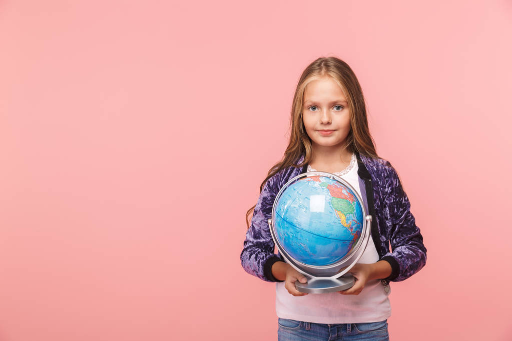 Smiling little girl standing isolated over pink background, holding earth globe - Photo, Image