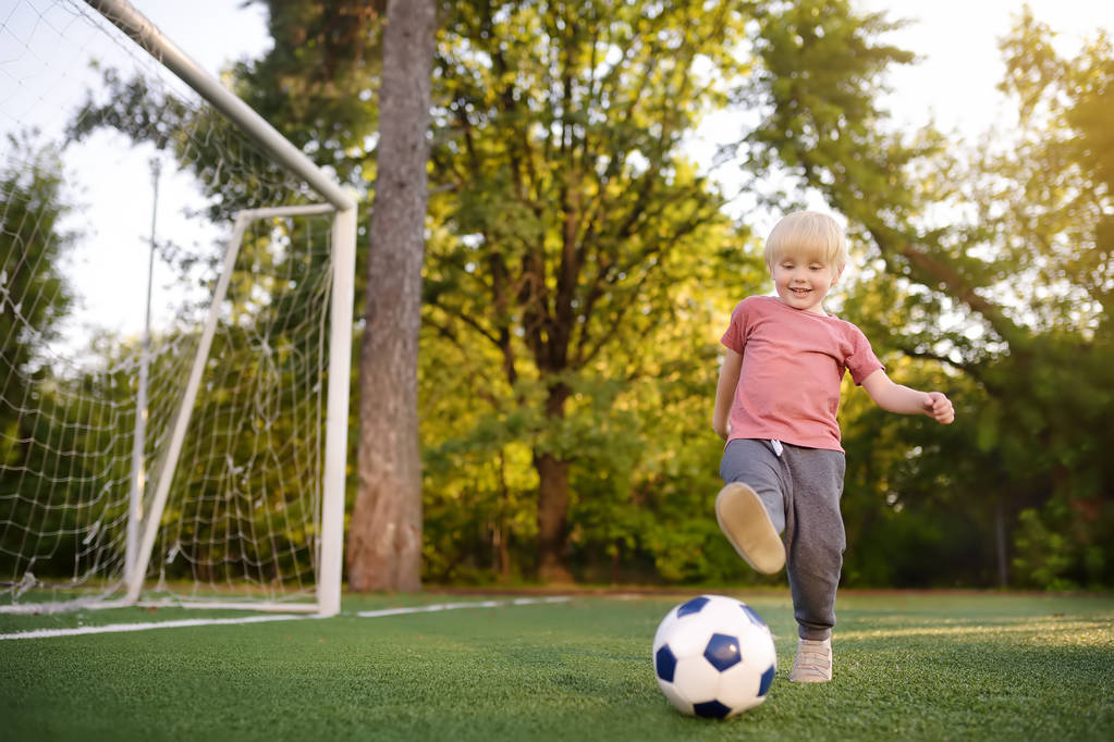 Jongetje plezier spelen van een voetbal/voetbalwedstrijd op zomerdag. Actieve buiten spel/sport voor kinderen. Kids voetbal klassen en kampen - Foto, afbeelding