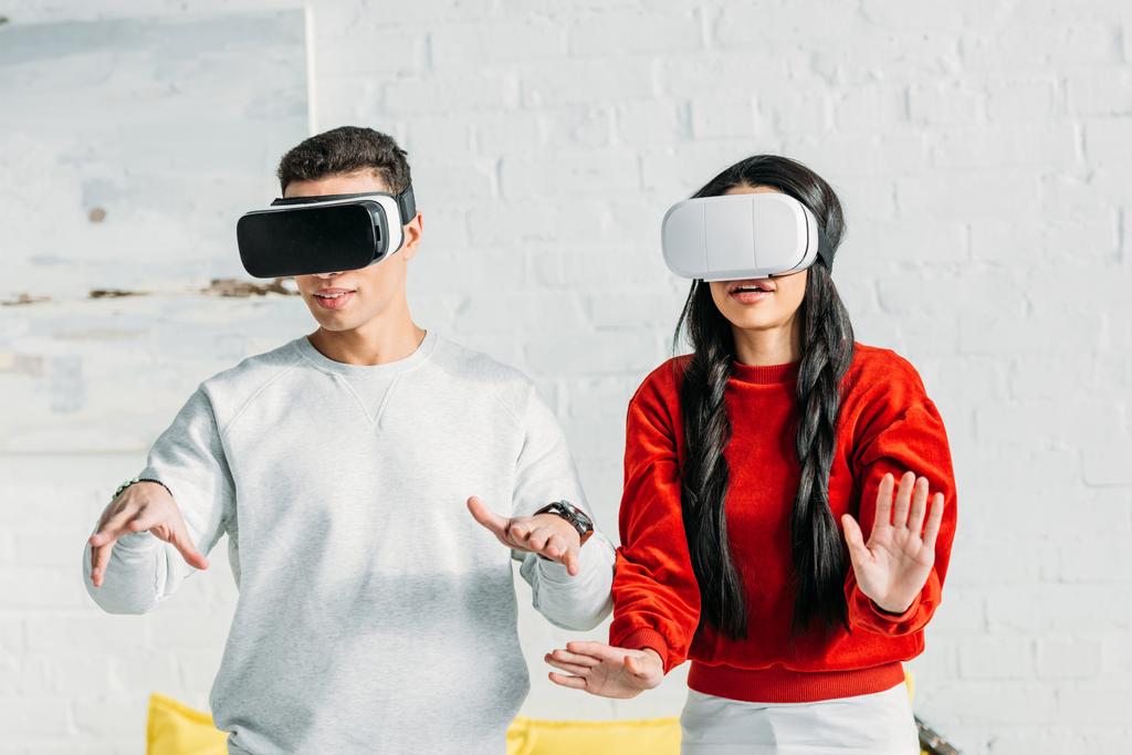 casal interracial se divertindo usando fones de ouvido realidade virtual em casa
  - Foto, Imagem