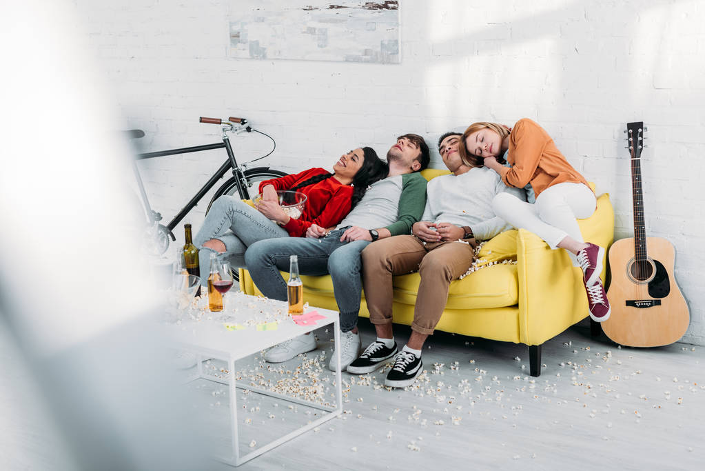 väsynyt monikulttuurinen ystävät nukkuvat keltainen sohva olohuoneessa
  - Valokuva, kuva