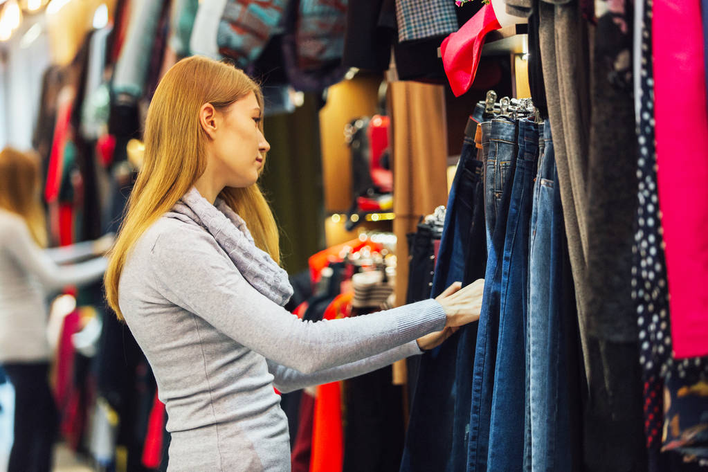 Woman with jeans and shopping in a fashionable clothing store. - Photo, Image