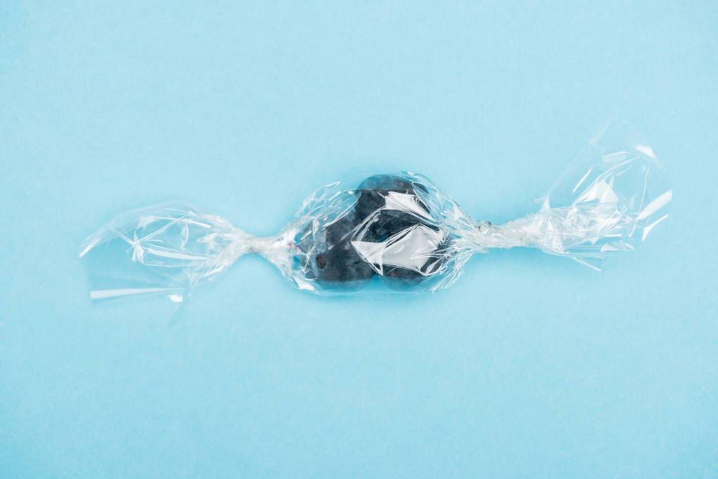 vista superior de arándanos en un envoltorio transparente en forma de caramelo sobre fondo azul
 - Foto, Imagen