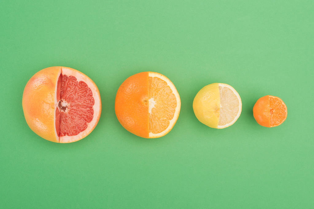 緑の背景に新鮮な部分的カット グレープ フルーツ、オレンジ、レモン、タンジェリンのトップ ビュー - 写真・画像