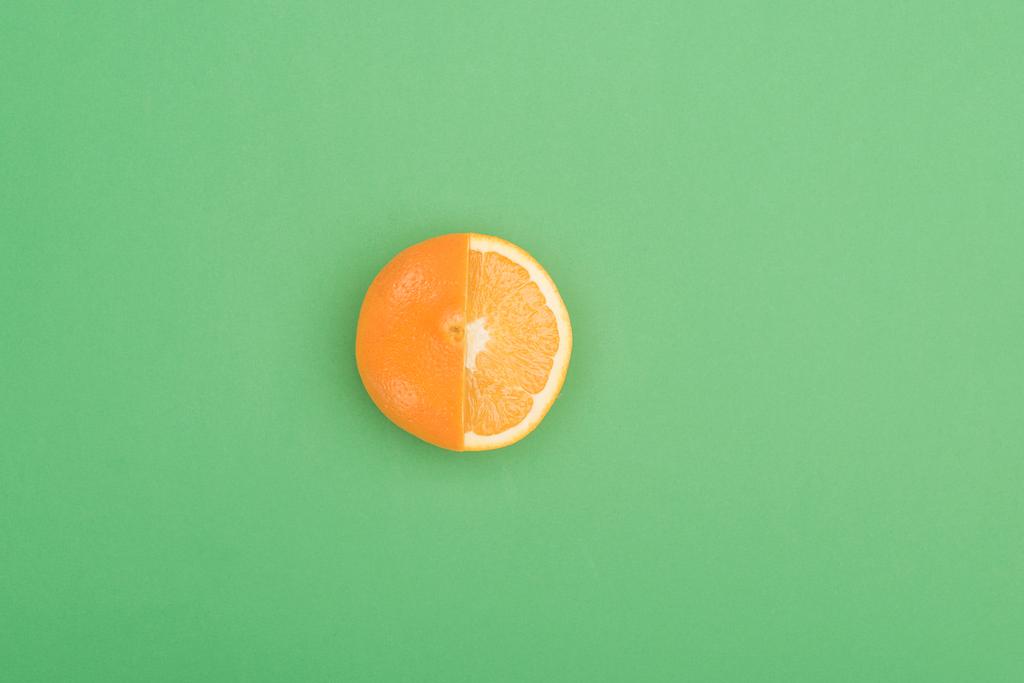 вид зверху на свіжий стиглий соковитий частково нарізаний апельсин на зеленому фоні
 - Фото, зображення