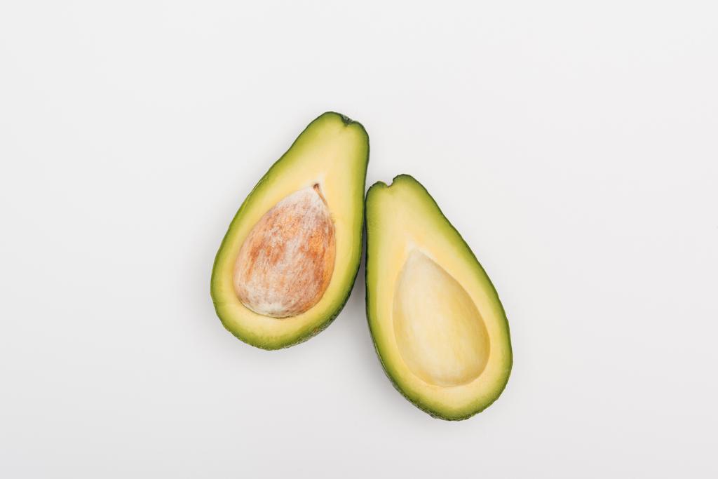 Draufsicht auf reife Avocadofruchthälften auf grauem Hintergrund - Foto, Bild