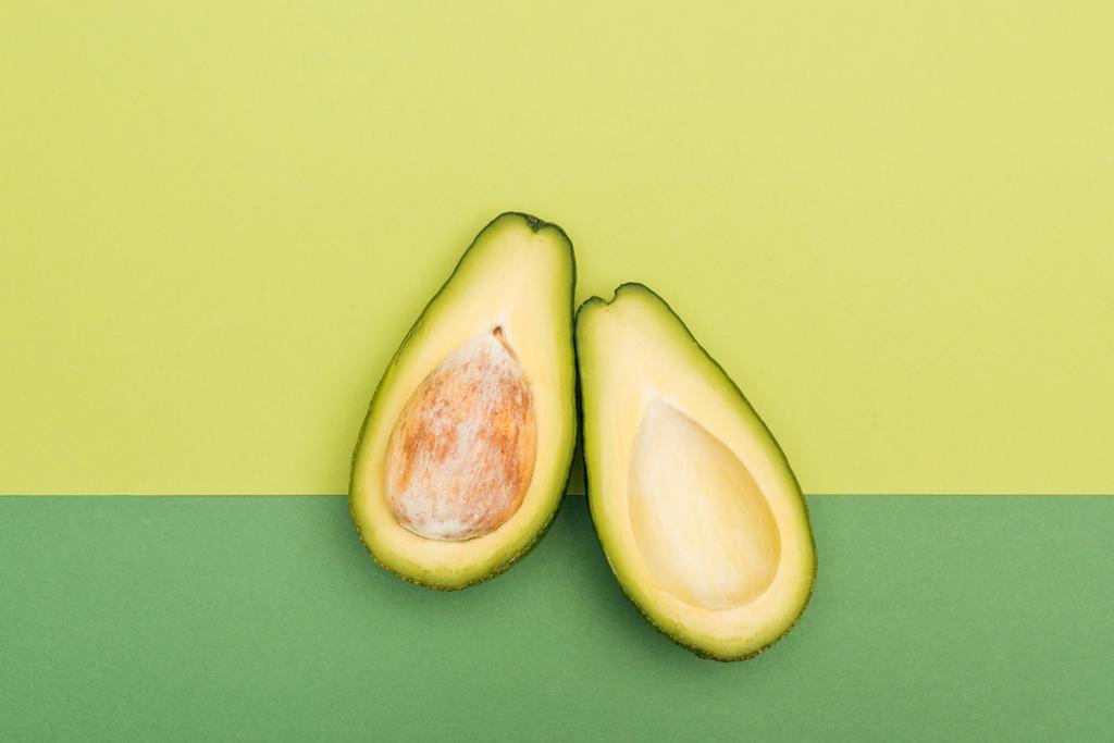 Draufsicht auf frische reife Avocadohälften auf zweifarbigem Hintergrund - Foto, Bild
