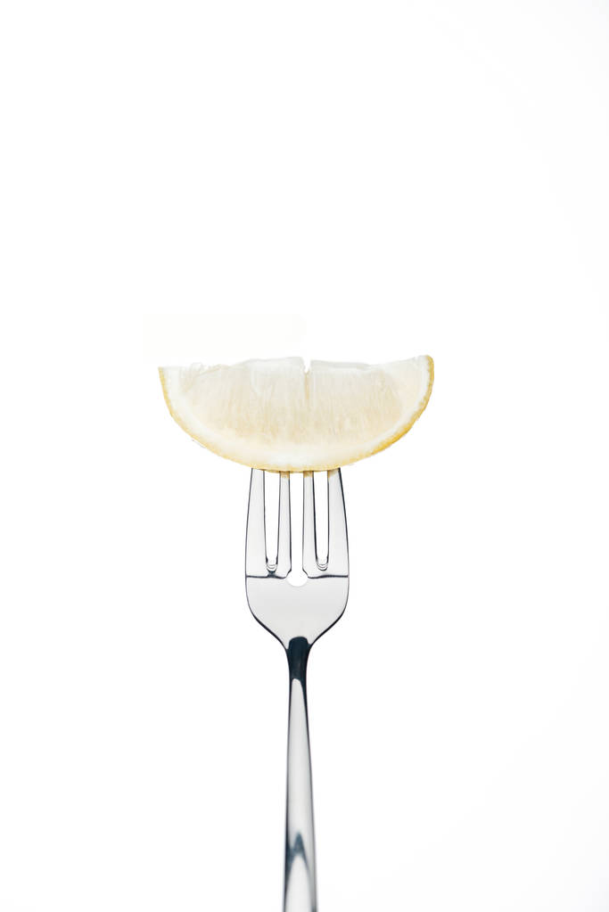 μισή φέτα φρέσκα ώριμα ζουμερό λεμόνι στο πιρούνι απομονωθεί σε λευκό - Φωτογραφία, εικόνα