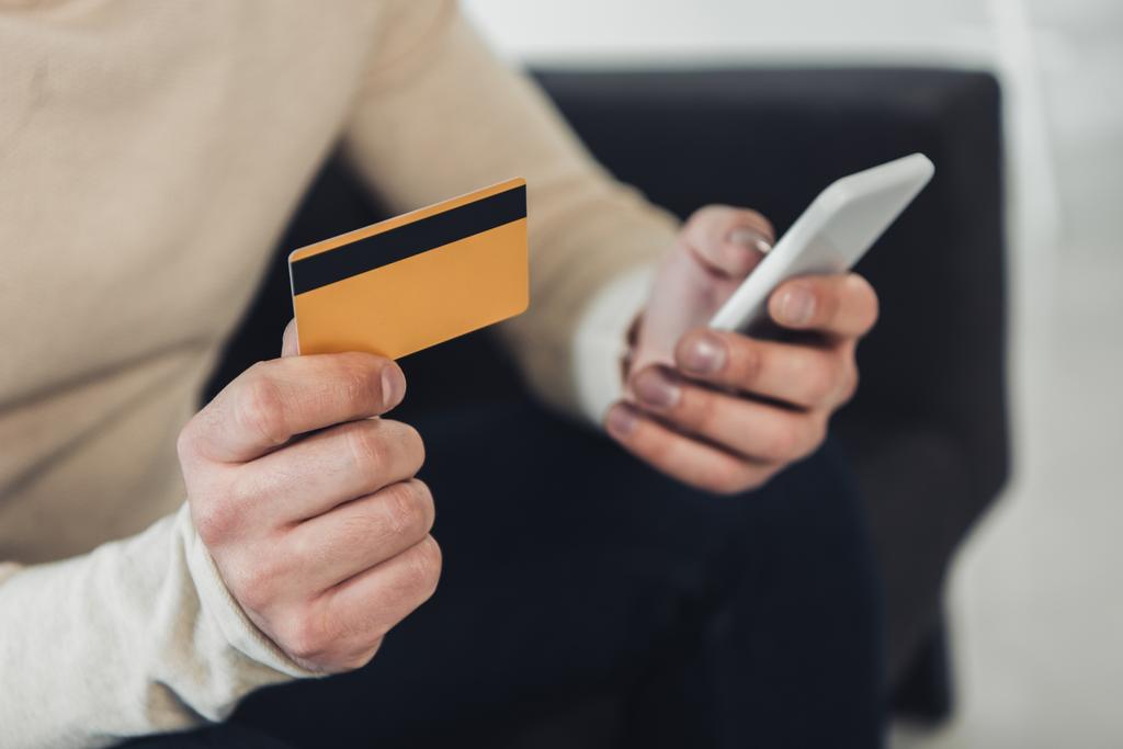 vista ritagliata di uomo in possesso di carta di credito e smartphone in mano
 - Foto, immagini
