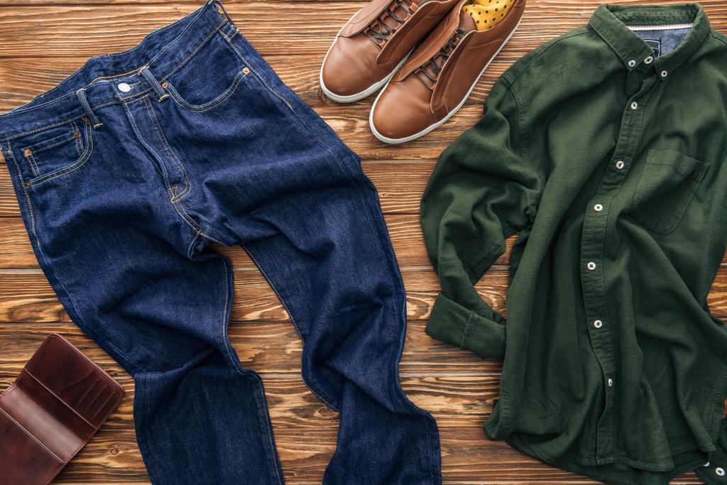 Κάτοψη του Τζιν, καφέ παπούτσια και πράσινο πουκάμισο σε φόντο ξύλινη - Φωτογραφία, εικόνα