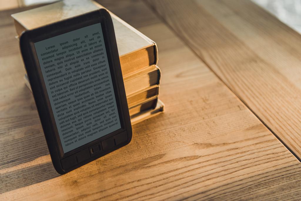 μαύρο ebook κοντά σε χαρτί βιβλία στο ξύλινο τραπέζι - Φωτογραφία, εικόνα