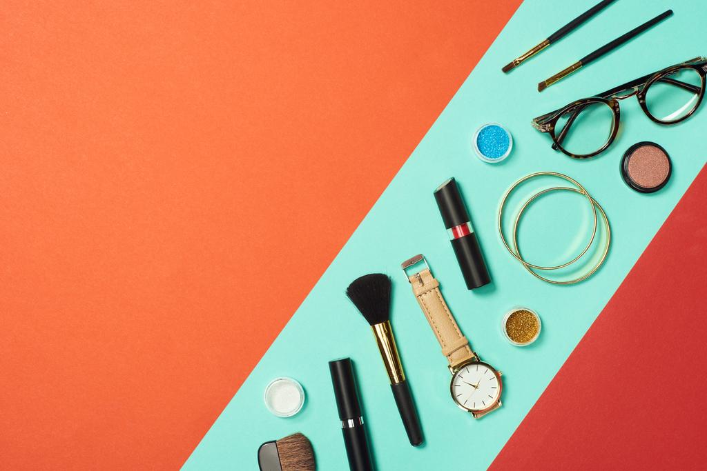 Mascara, horloge, lippenstift, armbanden, oogschaduw, blozen, bril en cosmetische penselen op turkooizen achtergrond - Foto, afbeelding