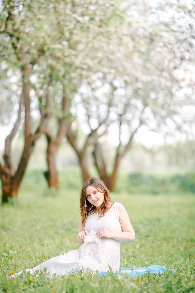 chica embarazada en vestido blanco sentado en la hierba y sonriendo
 - Foto, imagen