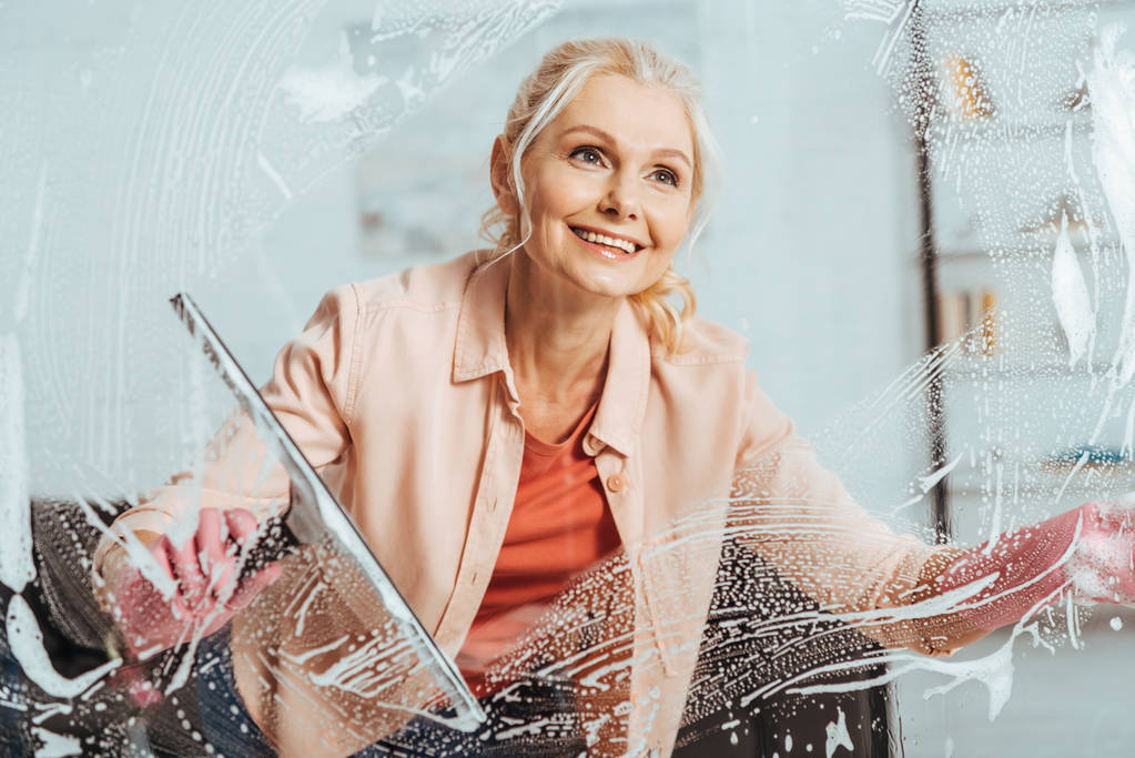 Janela de limpeza de mulher sorridente com limpador de vidro
 - Foto, Imagem