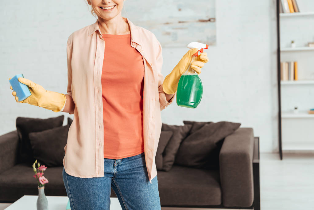 Partial view of woman in yellow rubber gloves holding cleaning spray and sponge - Photo, Image