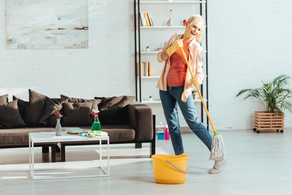 Laughing senior woman dancing while cleaning floor with mop - Photo, Image