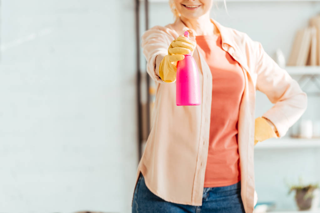 Обрізаний вид жінки в гумових рукавичках, що тримає рожеву пляшку
 - Фото, зображення