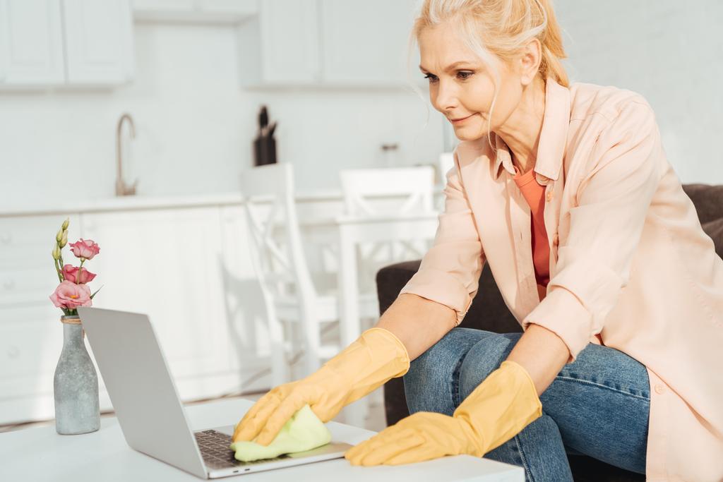 ノート パソコンのキーボードのクリーニング ゴム手袋で年配の女性 - 写真・画像