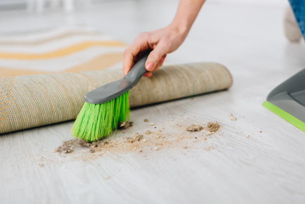 Περικοπεί shot γυναίκας σκουπίζοντας το πάτωμα με πράσινη βούρτσα - Φωτογραφία, εικόνα