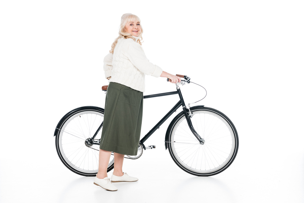 весела старша жінка, що стоїть з велосипедом ізольована на білому
 - Фото, зображення