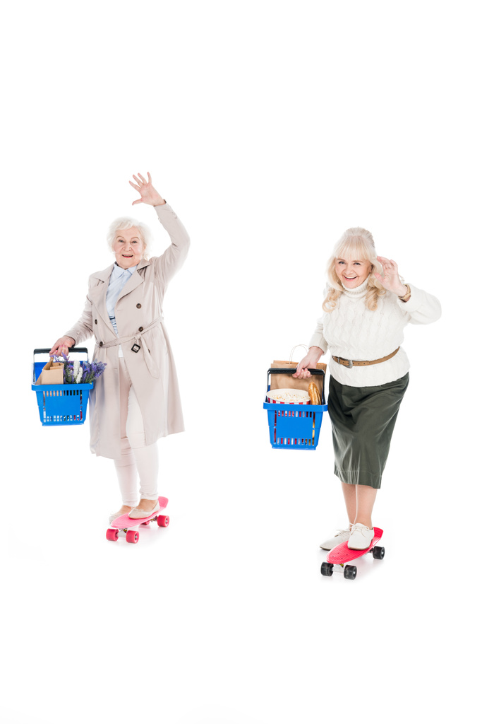 šťastné starší ženy na koni desek penny a drží nákupní košíky idolated na bílém - Fotografie, Obrázek