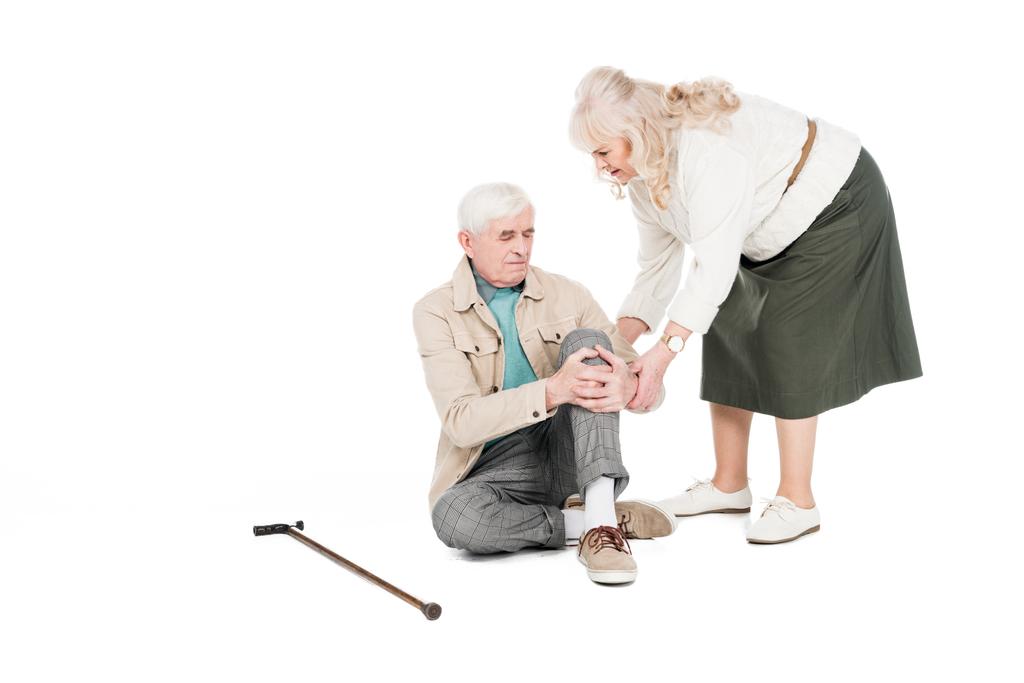 retirado hombre sosteniendo la rodilla mientras tiene artritis dolor cerca de cuidar esposa aislado en blanco
 - Foto, imagen