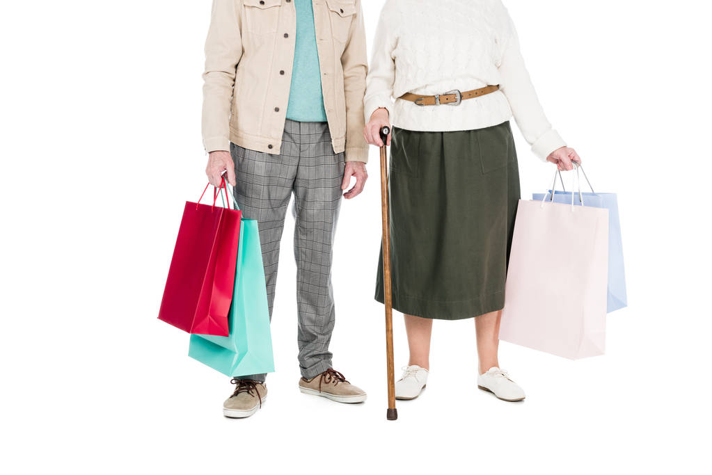 vista recortada de la pareja jubilada de pie con bolsas de compras aisladas en blanco
 - Foto, imagen