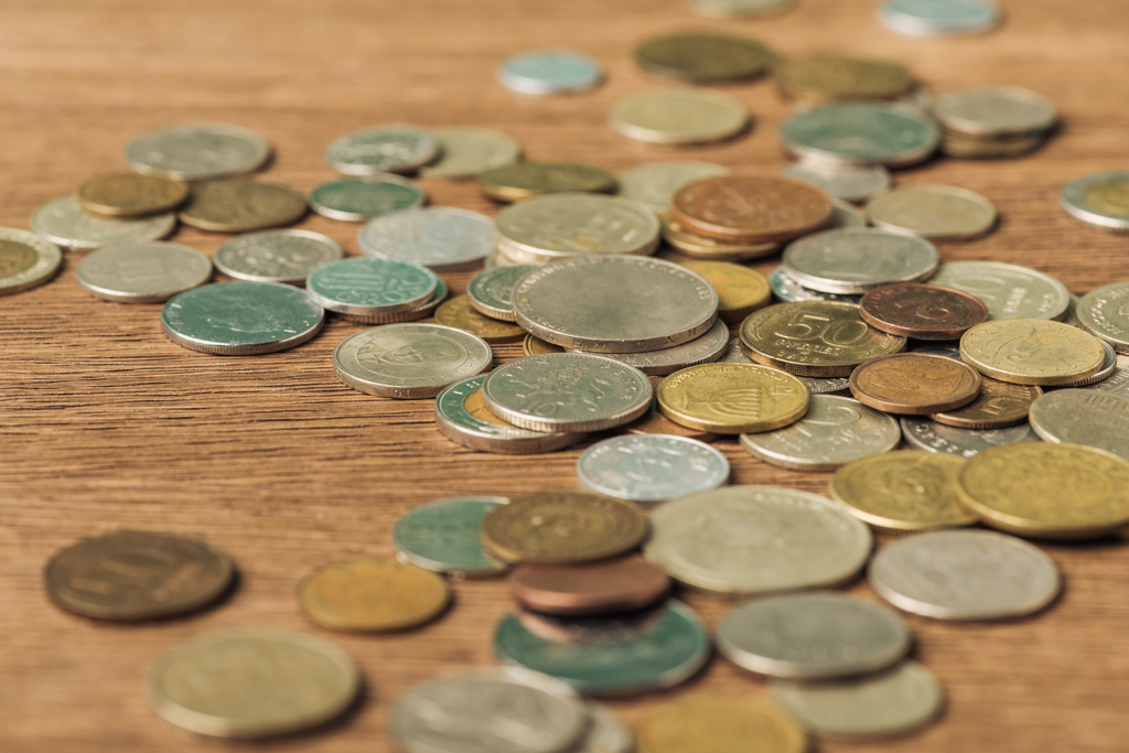 foco seletivo de diferentes moedas colocadas em fundo embaçado de madeira
 - Foto, Imagem