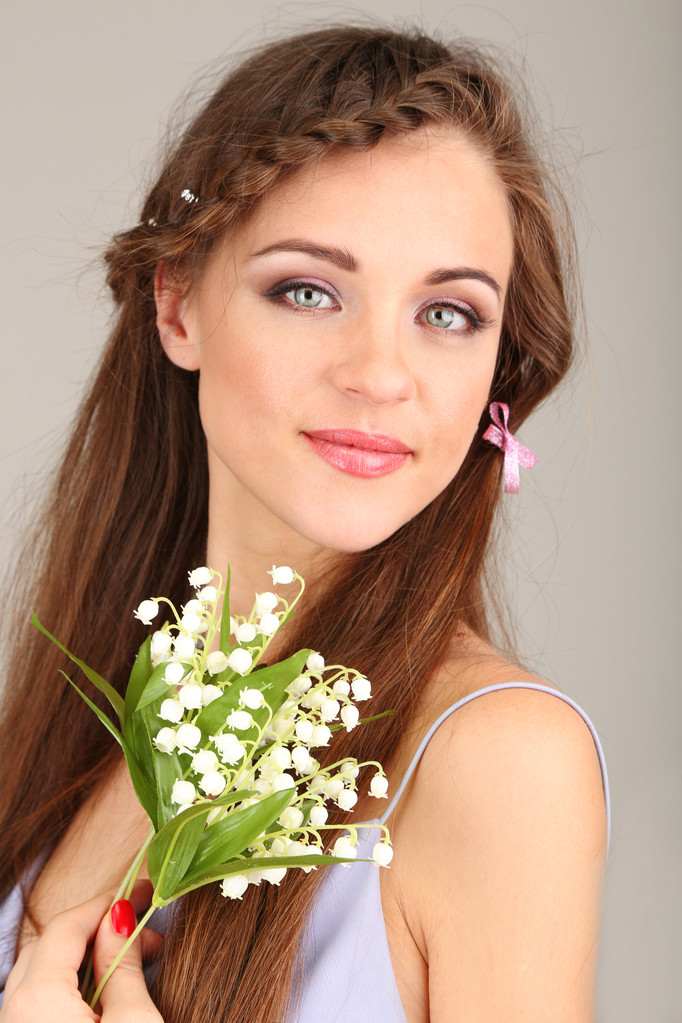 mladá žena s krásný účes a květiny, na šedém pozadí - Fotografie, Obrázek