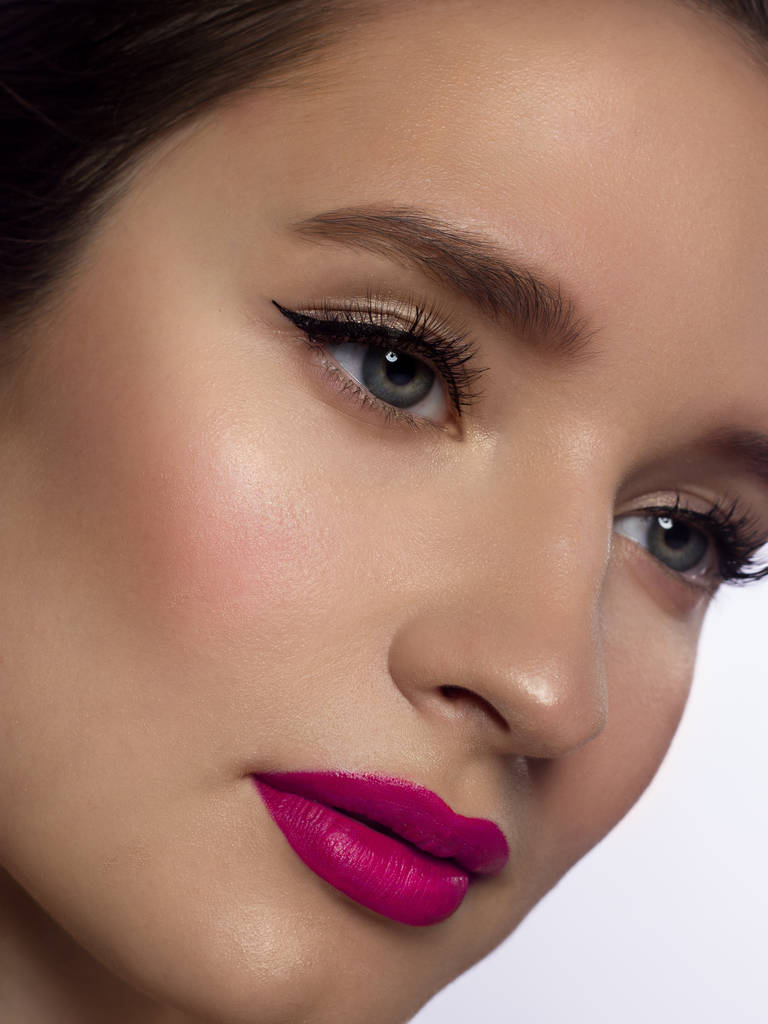 A close-up portrait of beauty with beautiful fashionable evening make-up, black snares on the eyes and extremely long eyelashes. pink lipstick on the lips. Cosmetology and spa facial skin care - Photo, Image