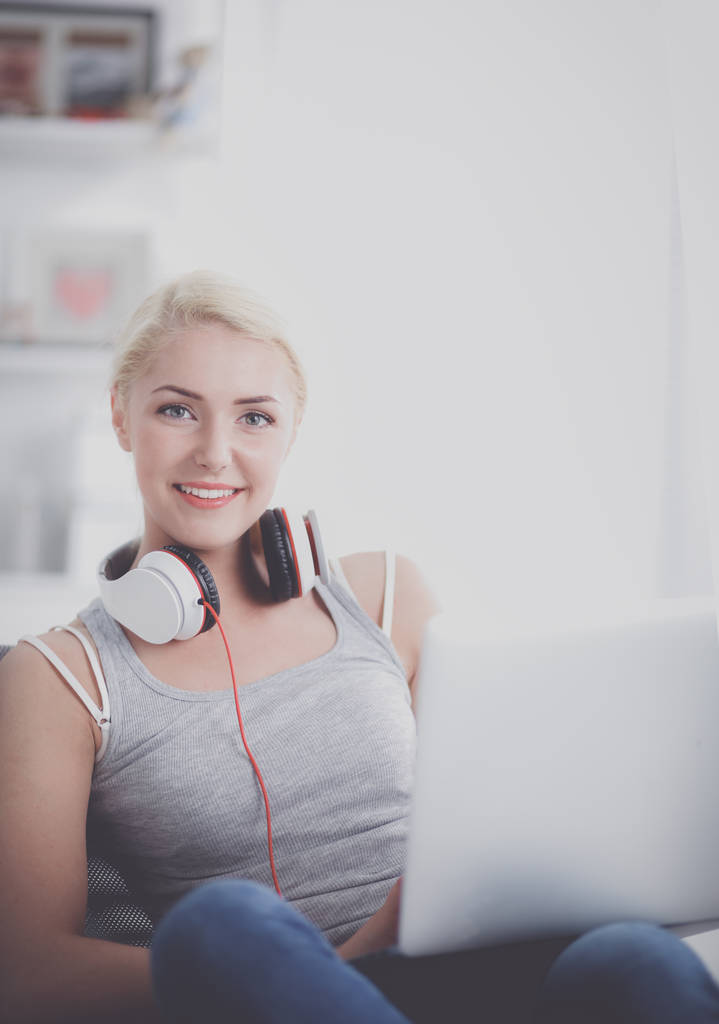 Young beautiful woman at home sitting on sofa and listening music - Photo, Image