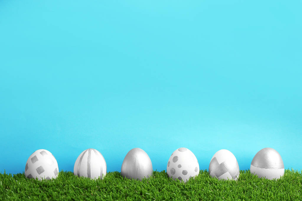 Línea de huevos de Pascua pintados sobre césped verde sobre fondo de color, espacio para texto
 - Foto, imagen