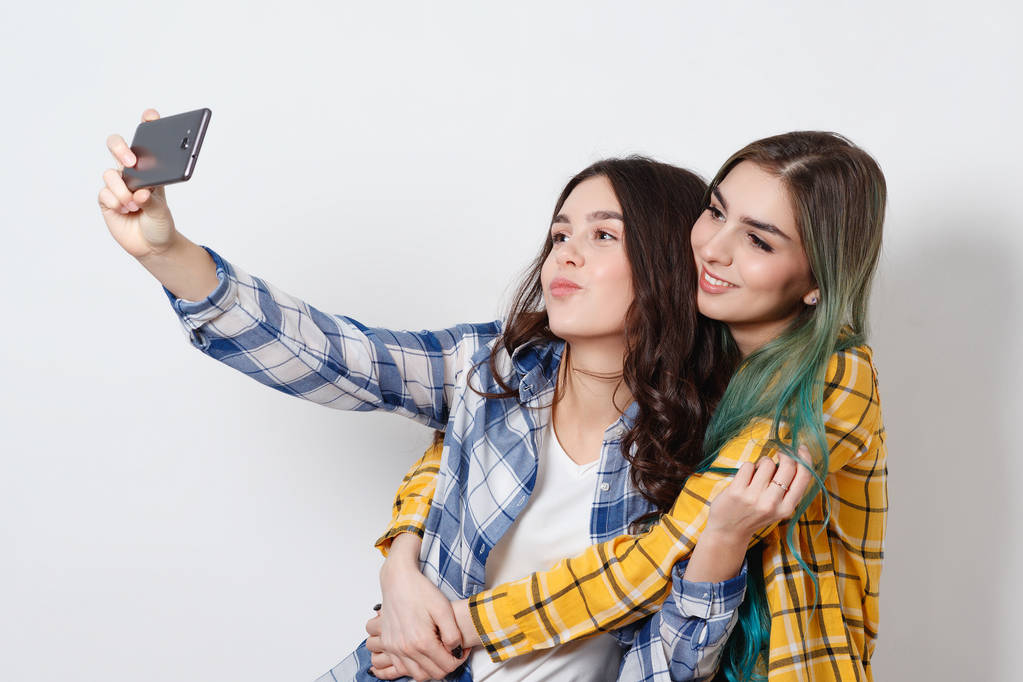 dvě mladé ženy užívající selfie s mobilním telefonem. na bílém pozadí - Fotografie, Obrázek