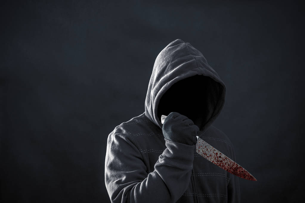 Homme à capuchon avec couteau sanglant dans le noir  - Photo, image