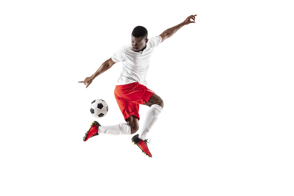 Afryki amerykański piłkarski gracz piłki w ruchu na białym tle na tle białego studia. Dopasowanie skoki człowieka w Akcja, skok, ruch w grze. - Zdjęcie, obraz