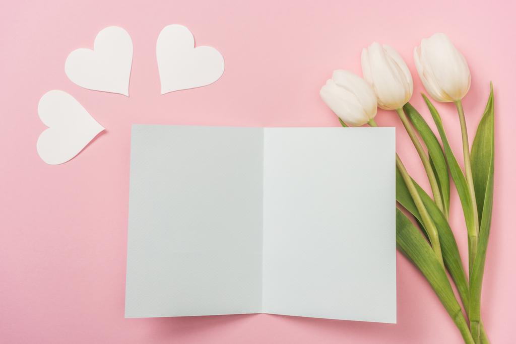 tarjeta de felicitación en blanco, corazones de papel blanco y tulipanes blancos sobre fondo rosa
 - Foto, Imagen