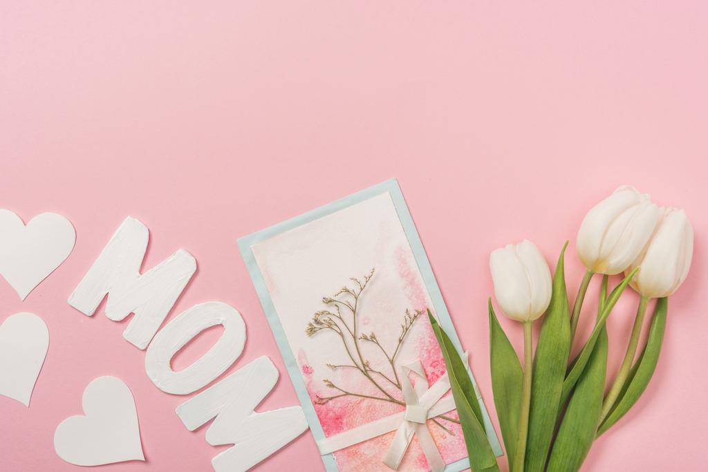 dia das mães cartão postal decorado com planta seca e arco, tulipas brancas, corações de papel e palavra mãe no fundo rosa
 - Foto, Imagem