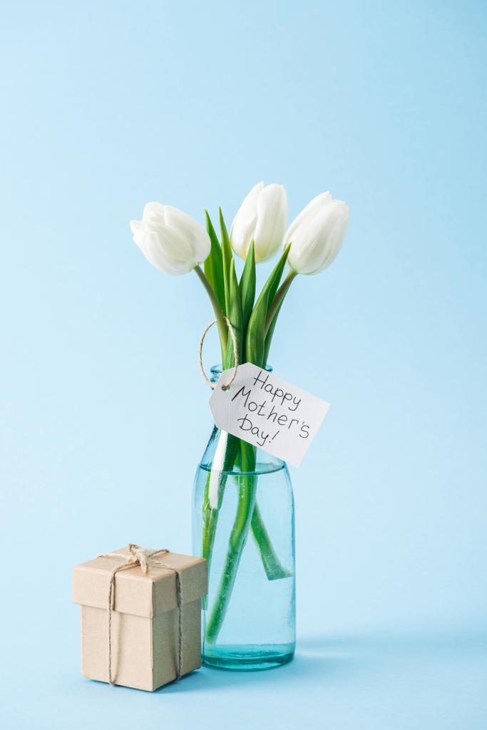hediye kutusu ve mutlu anneler günü tebrik etiketli mavi zemin üzerine beyaz lale buketi - Fotoğraf, Görsel