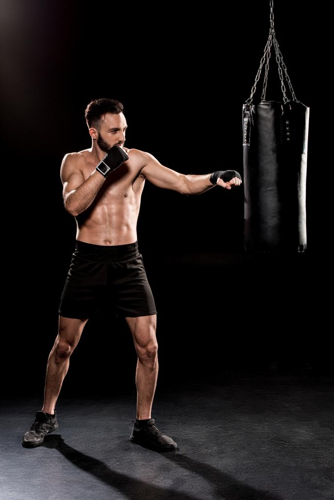 boxer barbuto esercizio con sacco da boxe su sfondo nero
 - Foto, immagini