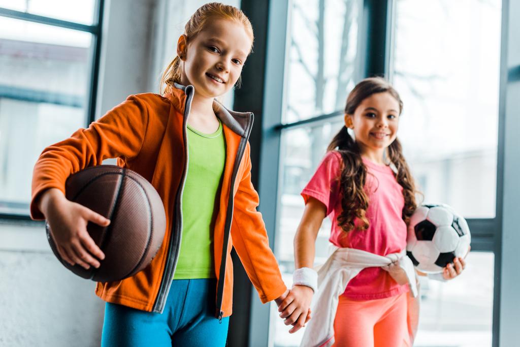 Cute kids with balls holding hands in gym - Photo, Image