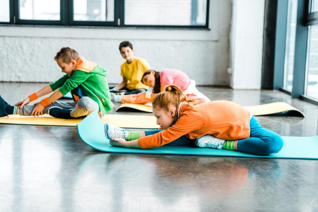 Grupo de crianças que se alongam em tapetes de fitness coloridos
 - Foto, Imagem