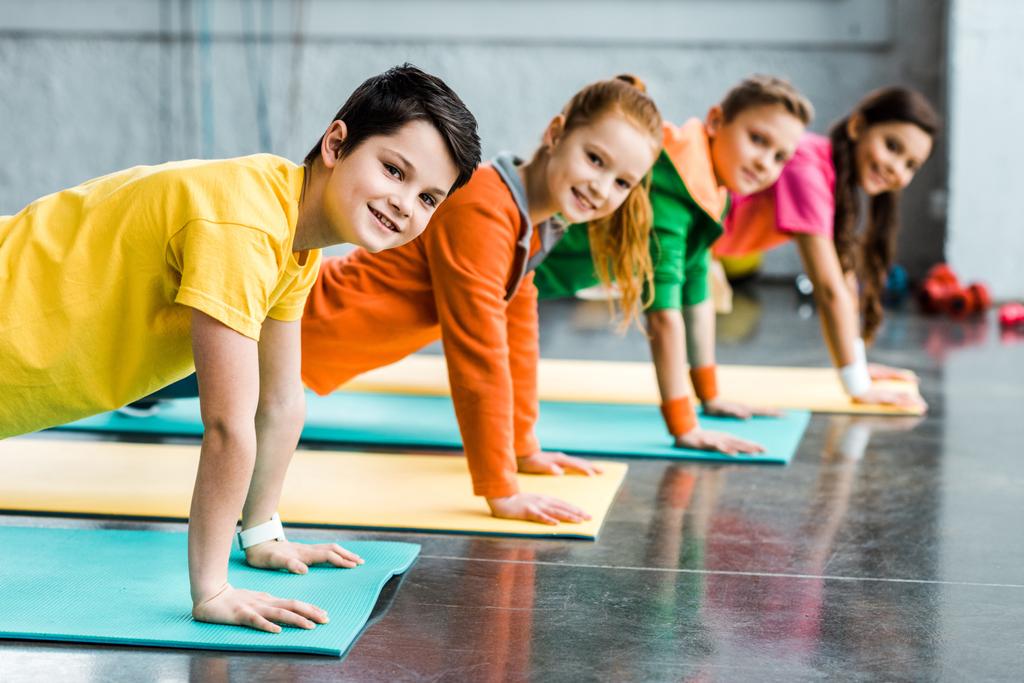 Veselé děti dělá prkno cvičení a při pohledu na fotoaparát - Fotografie, Obrázek