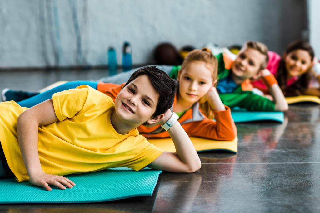 Radostné děti ležící na fitness rohože a při pohledu na fotoaparát - Fotografie, Obrázek