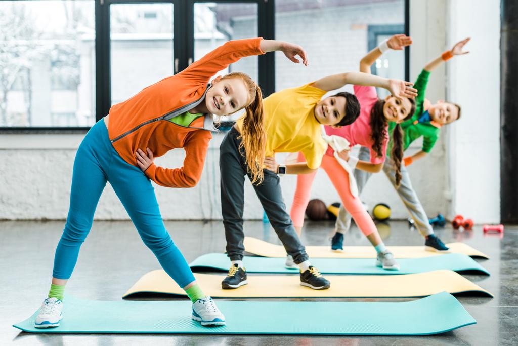 Smiling preteen kids doing sport exercise together  - Photo, Image