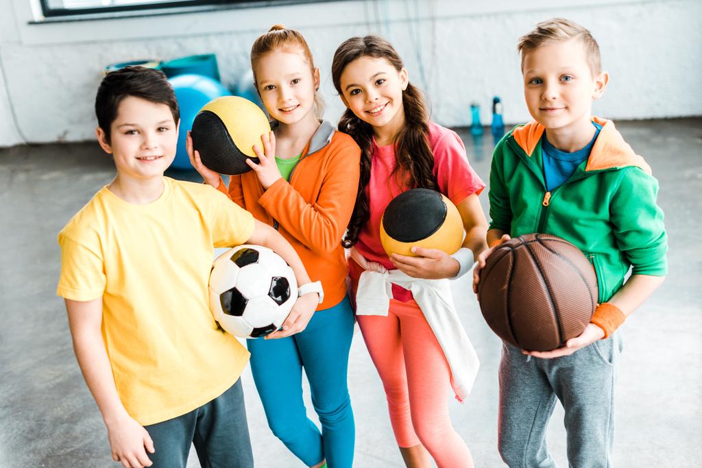 Ενθουσιασμένοι παιδιά σε αθλητικά ρούχα, ποζάρει με μπάλες - Φωτογραφία, εικόνα