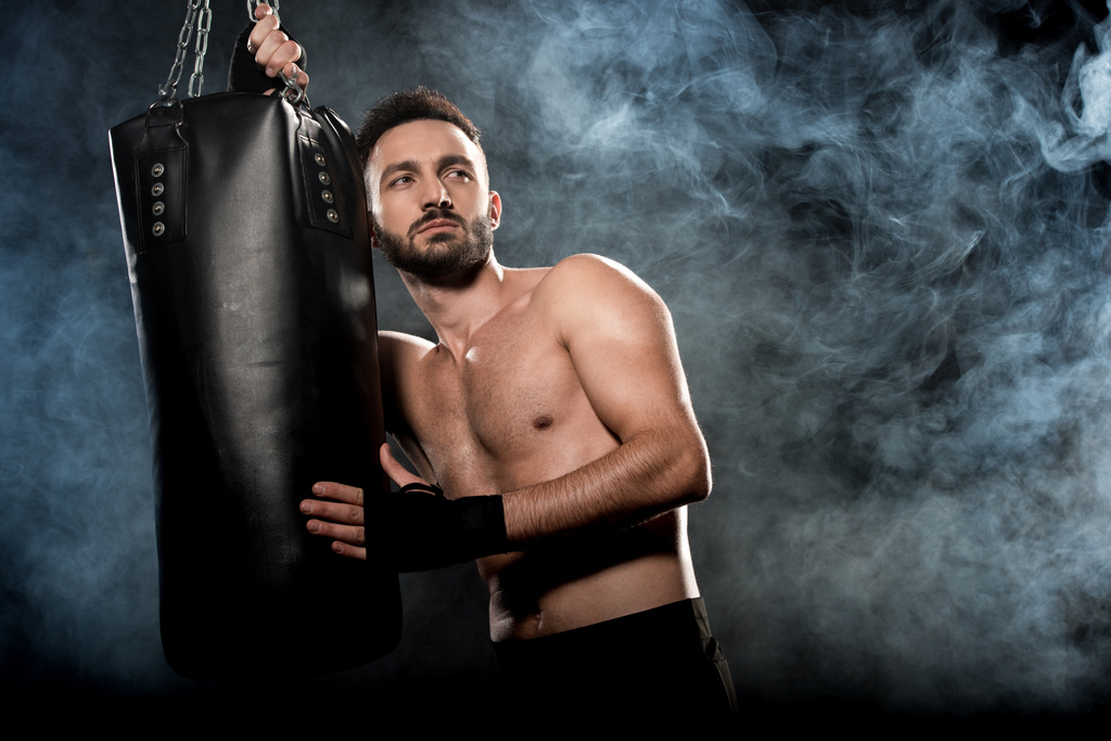 пенсійний спортивний боксер тримає ударну сумку на чорному з димом
 - Фото, зображення