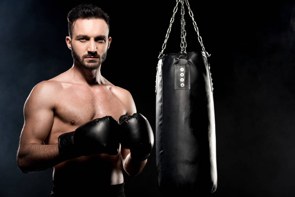 knappe atleet in bokshandschoenen permanent in boksen pose geïsoleerd op zwart - Foto, afbeelding