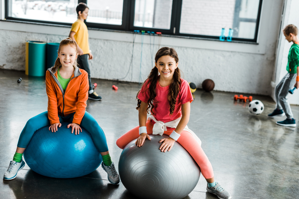 Enfants posant avec le sourire assis sur des boules de fitness
 - Photo, image