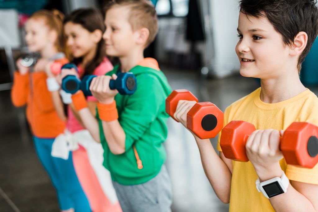 Lindos niños entrenando con pesas de colores
 - Foto, imagen